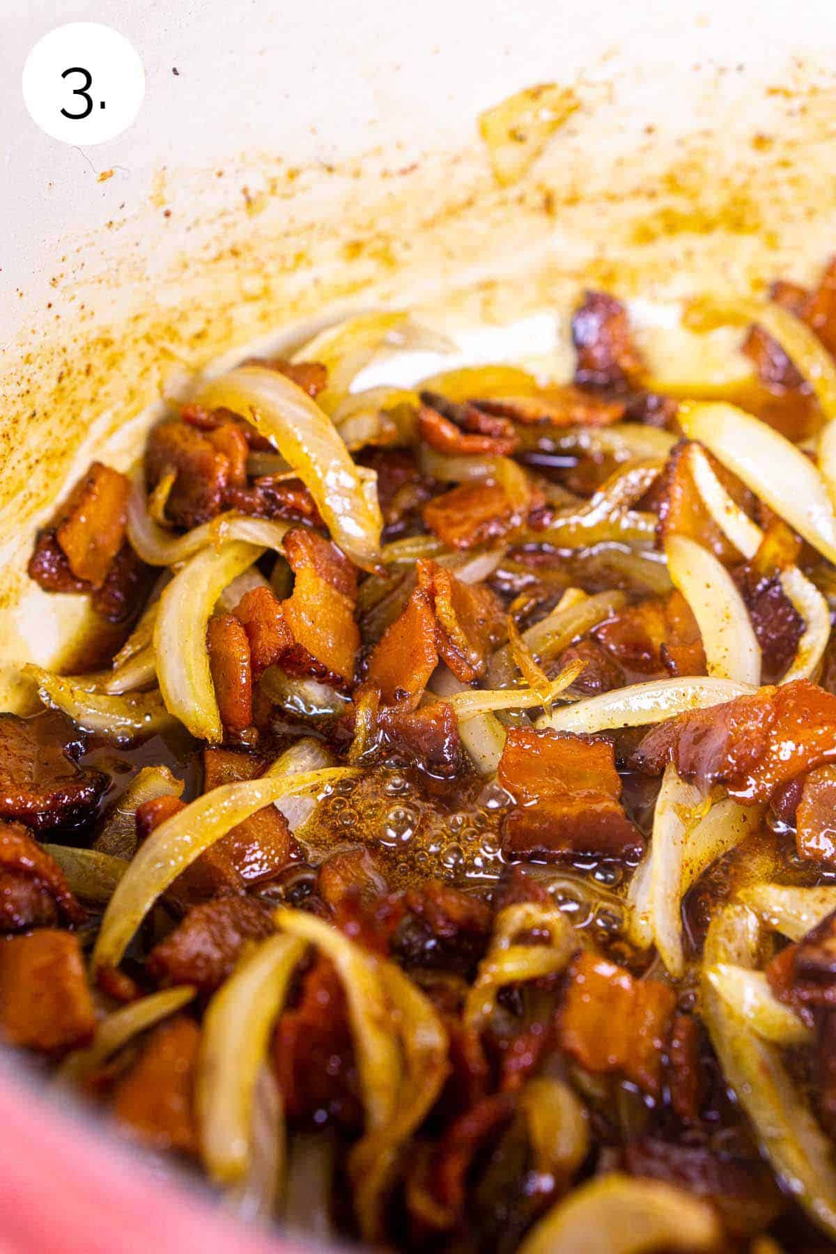 The bacon and caramelized onions with the liquid ingredients added to a large red Dutch oven on the stove.