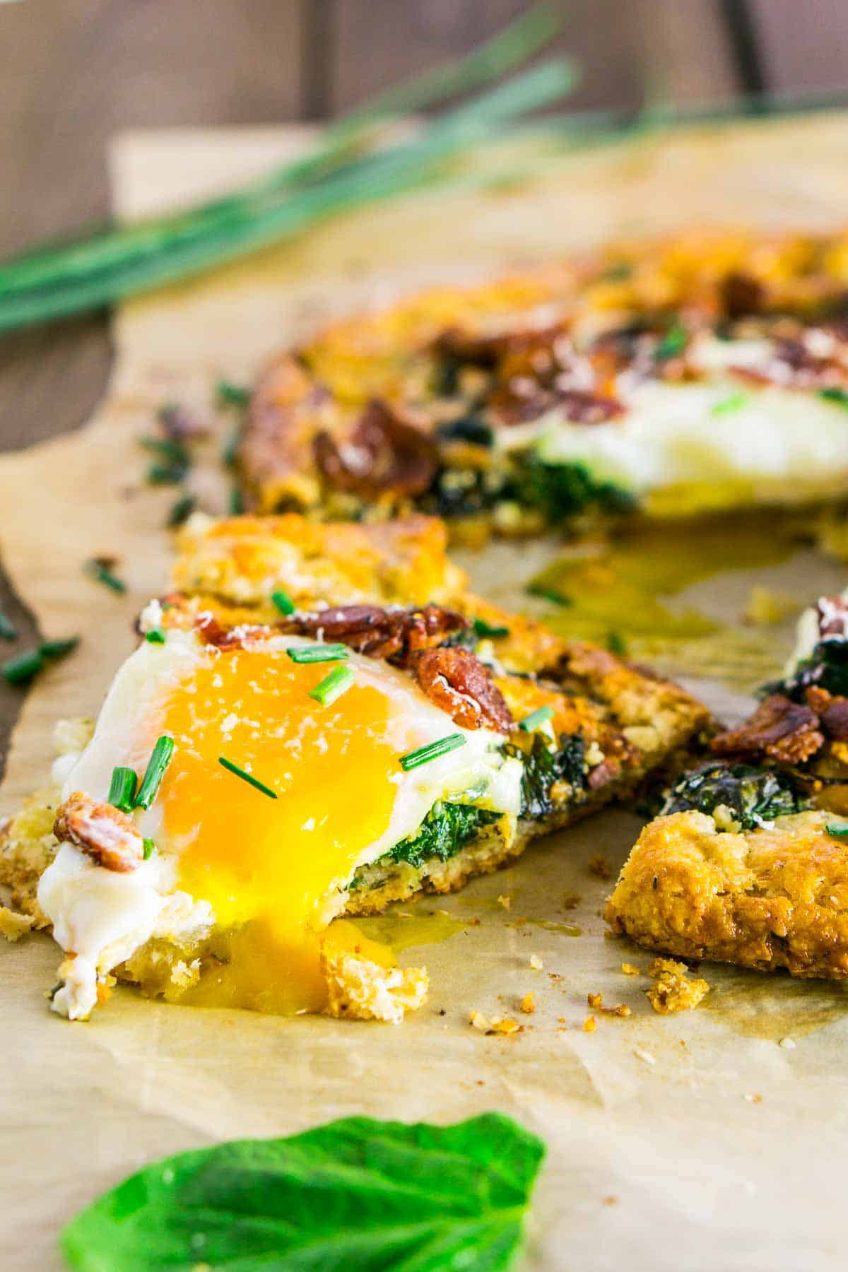 A slice of the breakfast galette with the egg yolk oozing down the side on a large sheet of brown parchment paper.