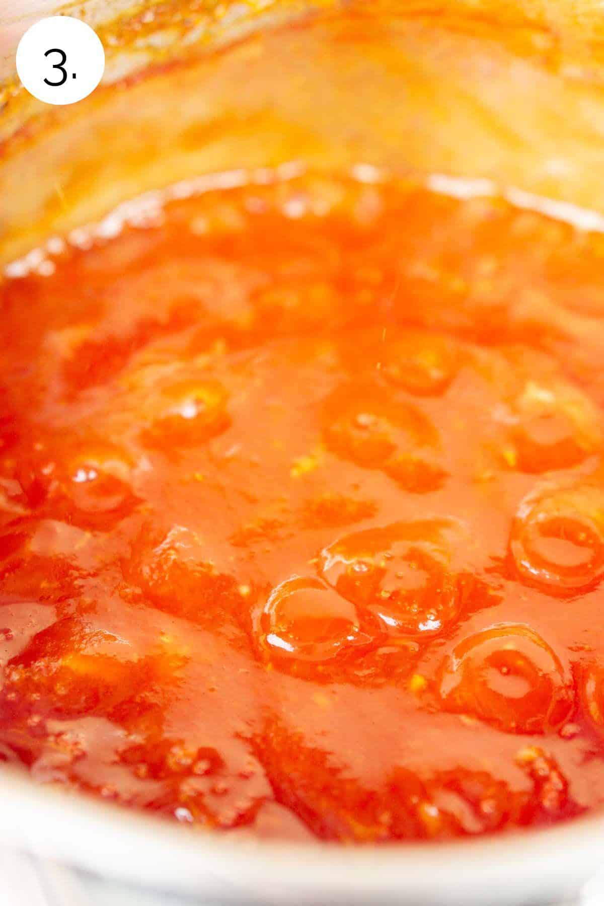 Simmering the sauce in a small stainless steel sauce pan on the stove-top range in the kitchen.