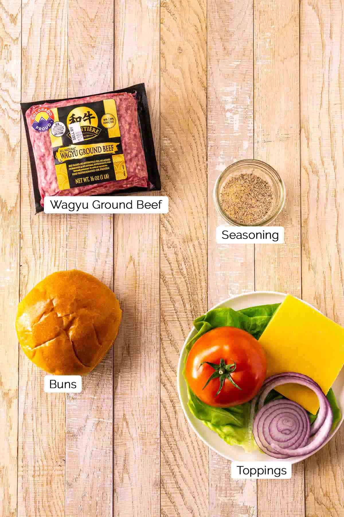 The burger ingredients on a cream-colored wooden surface with black and white labels underneath the items.
