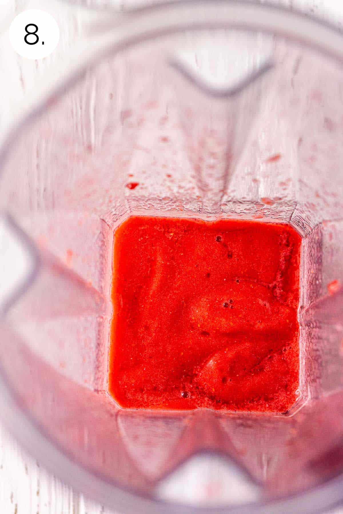 The frozen daiquiri in the blender on a white wooden surface after the ingredients have been processed until smooth.