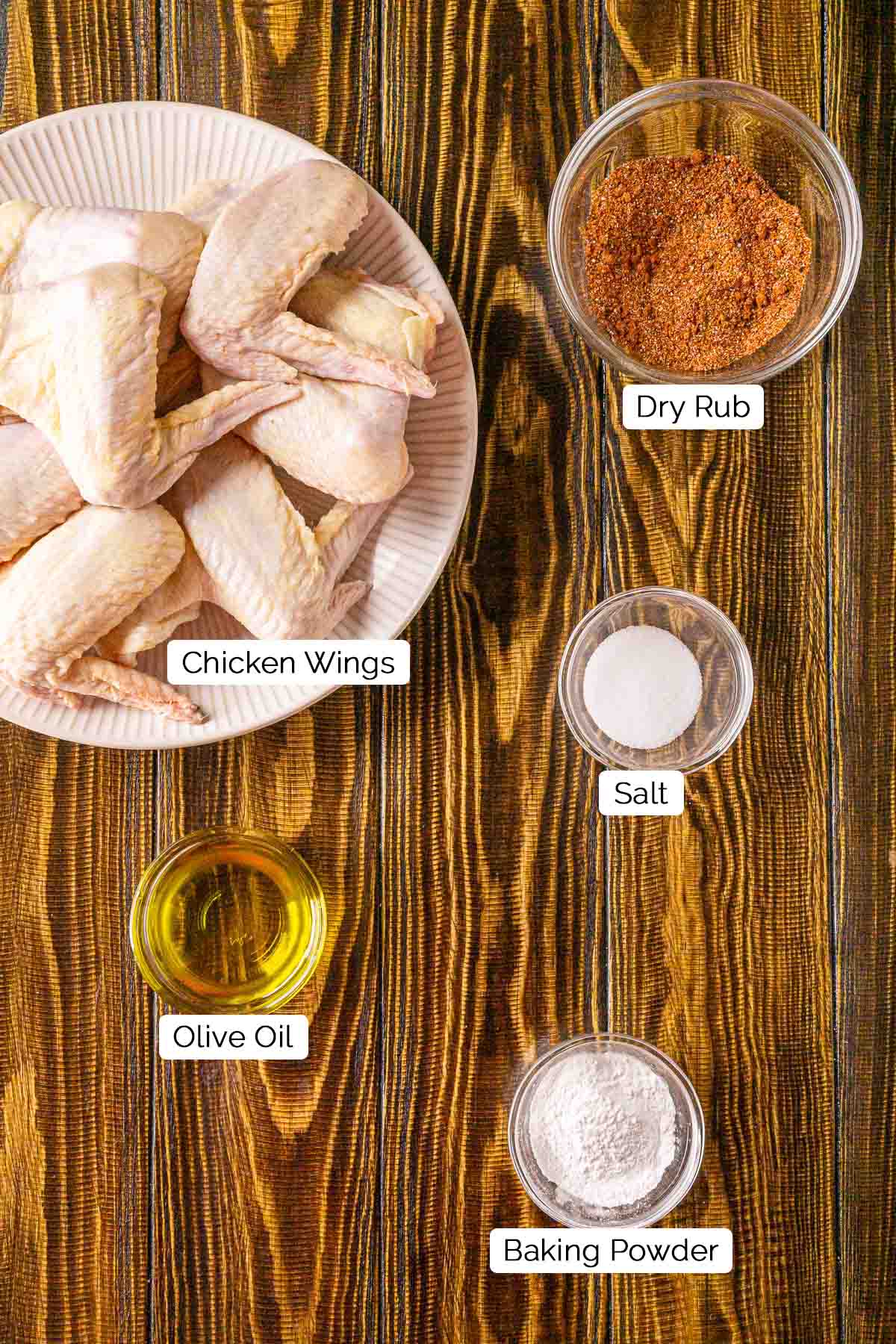 The ingredients on a brown wooden board with black and white labels by each item.