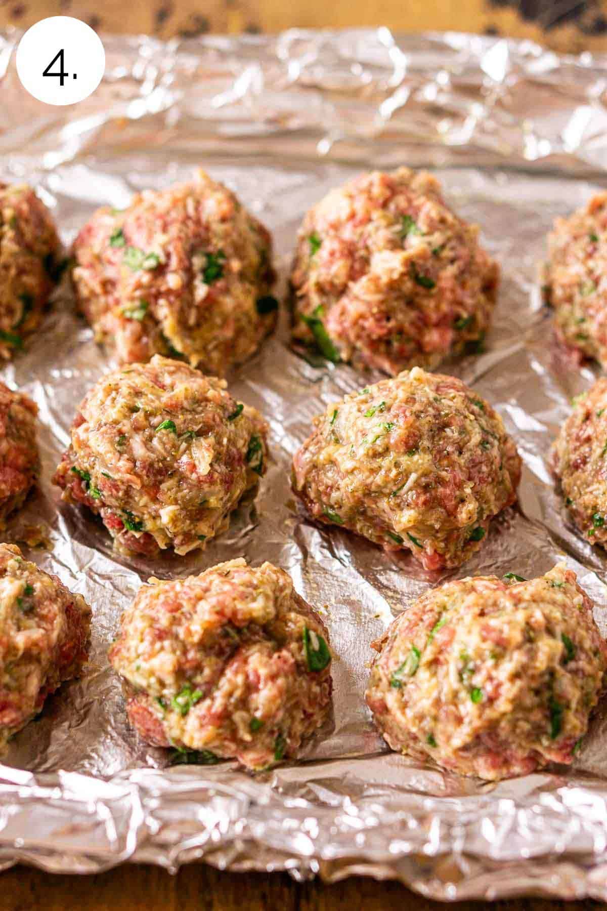 The uncooked meatballs on a baking sheet lined with aluminum foil before going into the smoker.