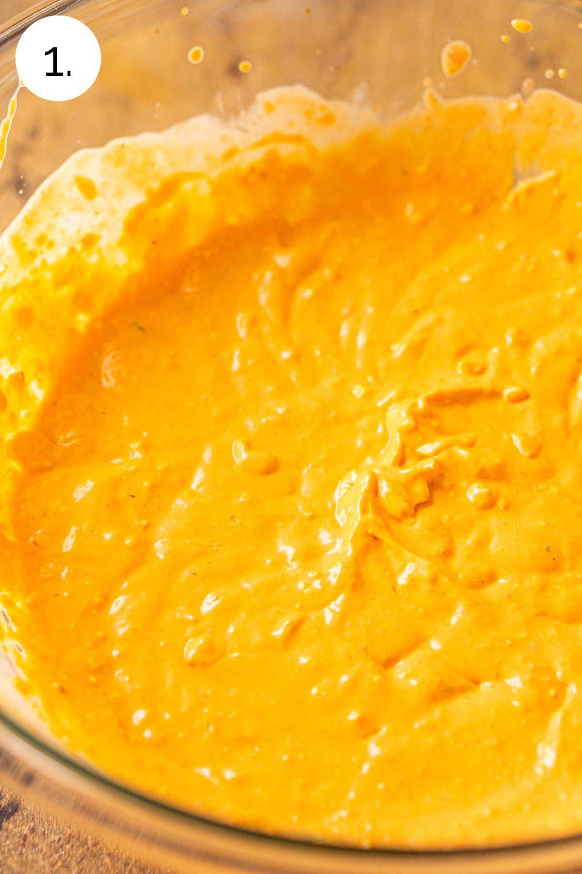 The cream cheese and hot sauce mixture in a large mixing bowl after the ingredients have been mixed together.