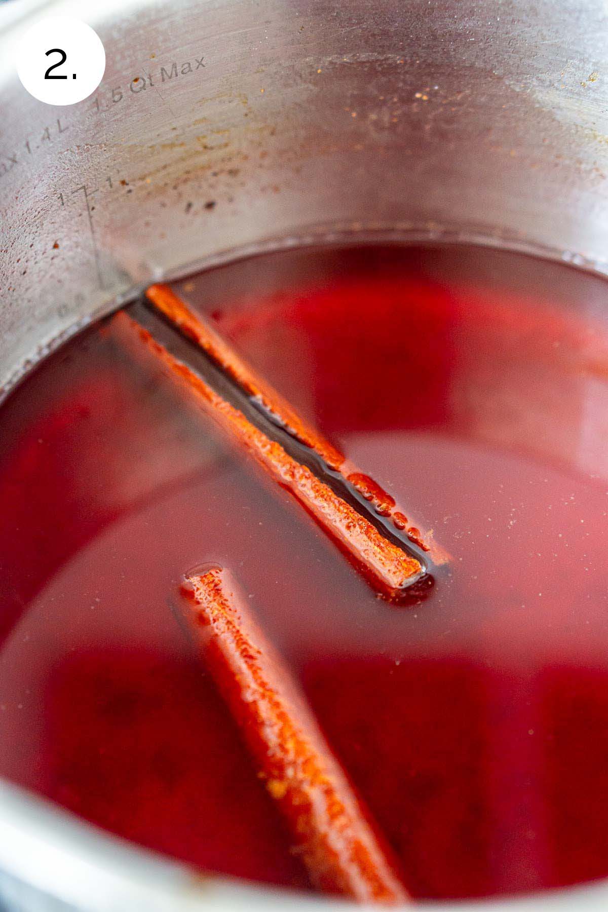Steeping the cranberry juice in a small stainless steel saucepan with the cinnamon sticks and spices.