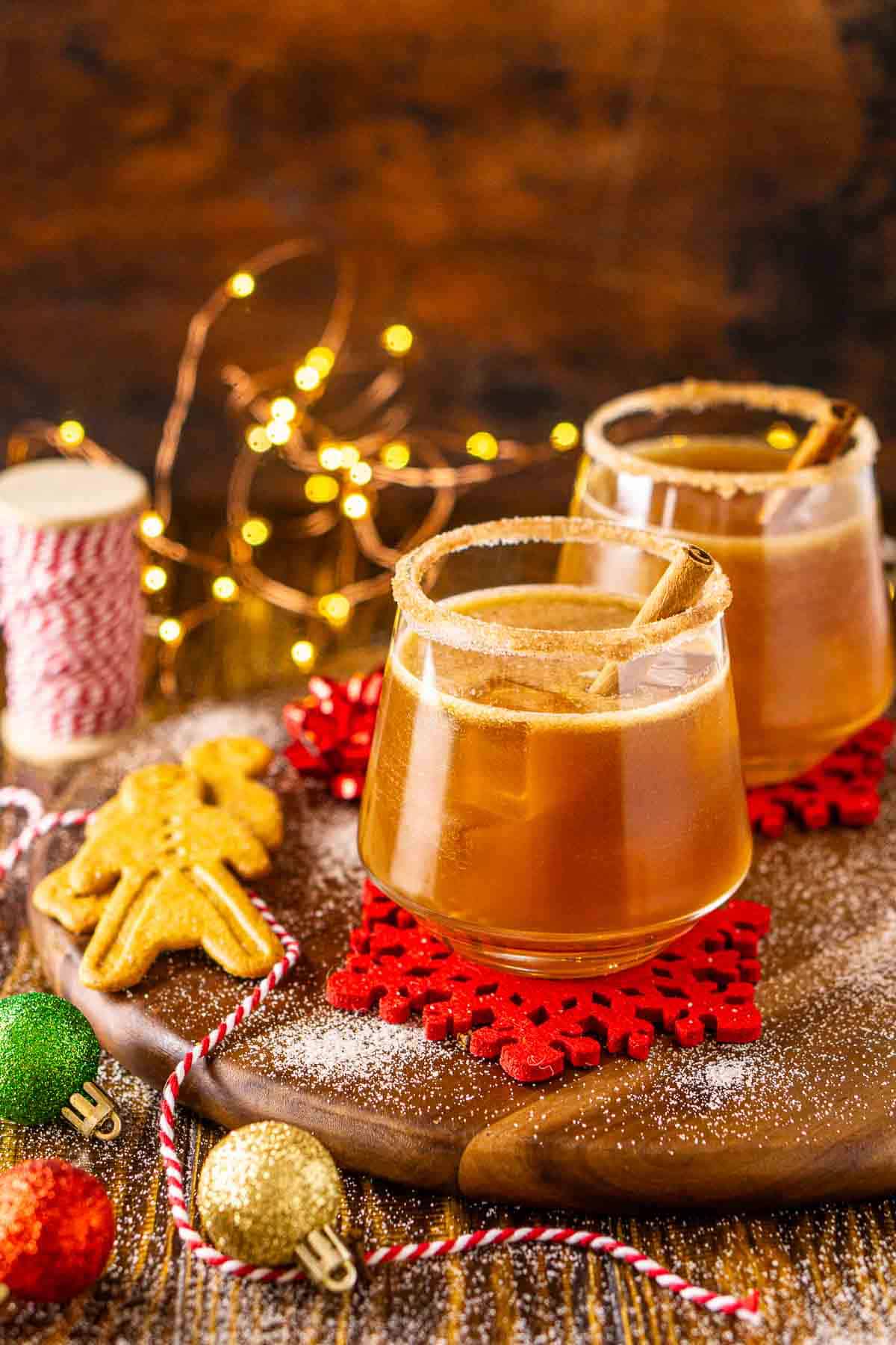 A gingerbread margarita with holiday decor around it with cinnamon and sugar sprinkled around it.