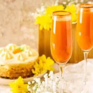 Two carrot cake mimosas on white lace with yellow flowers to the side and a small cake in the background.
