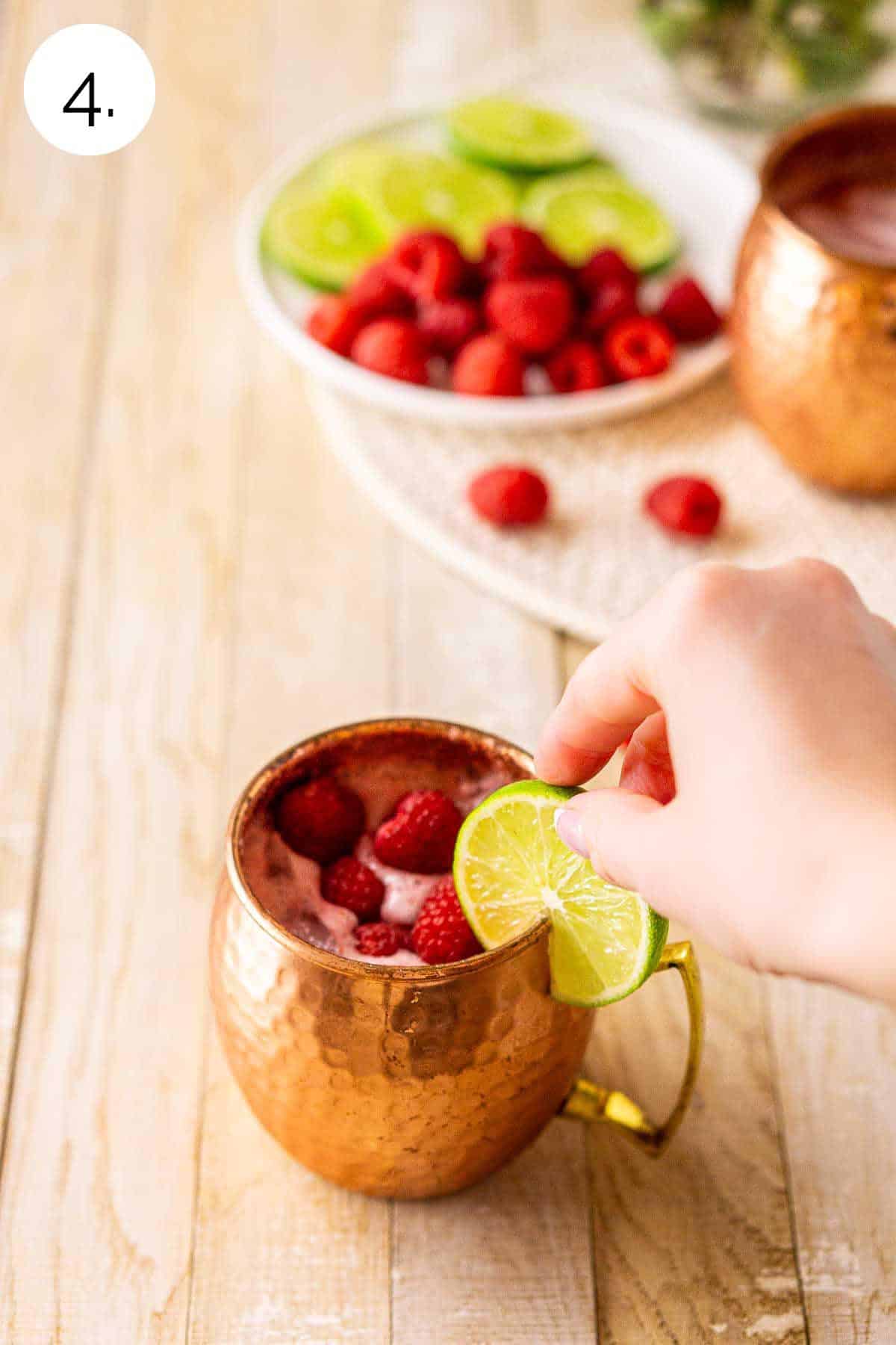 Adding a lime wheel to the finished drink with a few fresh raspberries on top.