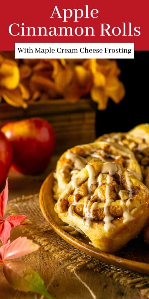 An apple cinnamon roll on a small wooden plate with fall leaves around it and text overlay on top of the image.