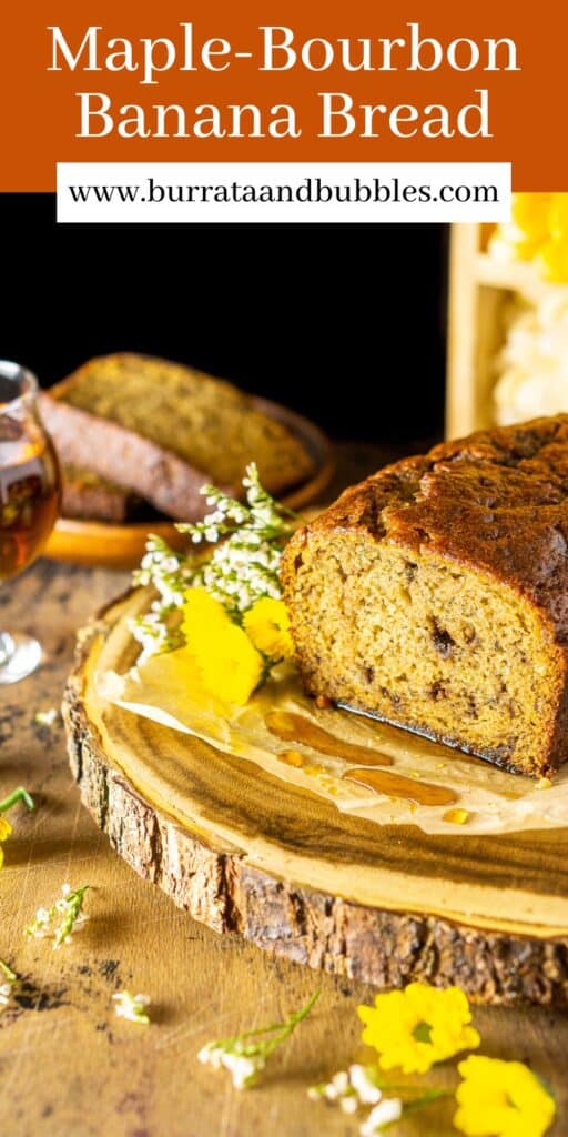 A loaf of maple-bourbon banana bread on a wooden platter with flowers surrounding it and text overlay on top.