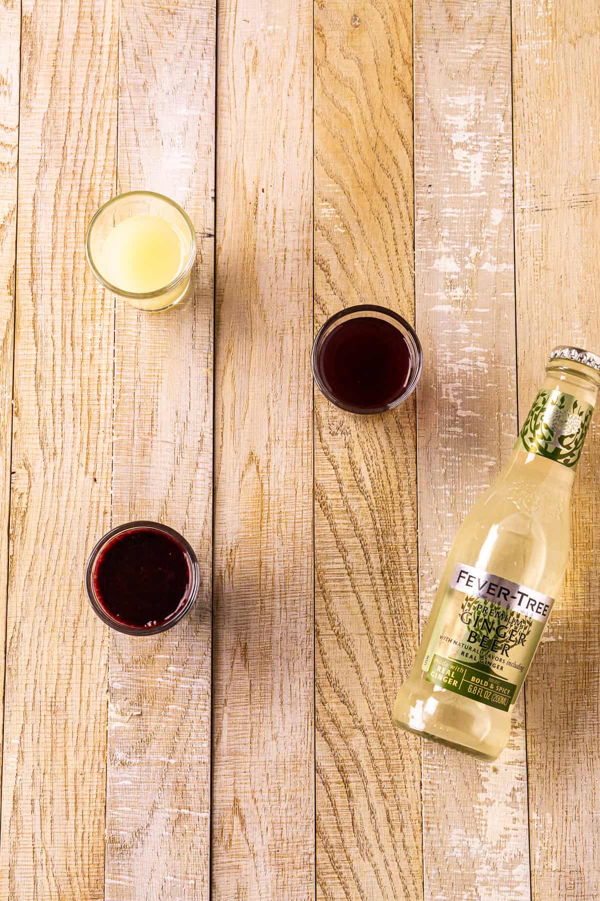 The blackberry Moscow mule ingredients positioned on a cream-colored wooden board before making the drink.