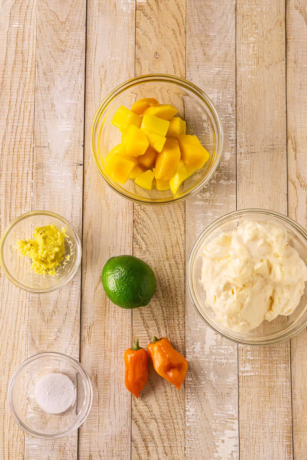 The ingredients for the aioli on a cream-colored wooden surface.