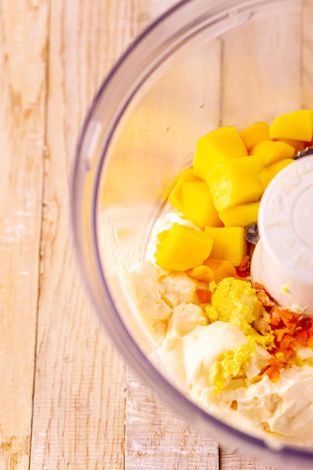 The ingredients in a food processor before blending to make a smooth sauce.