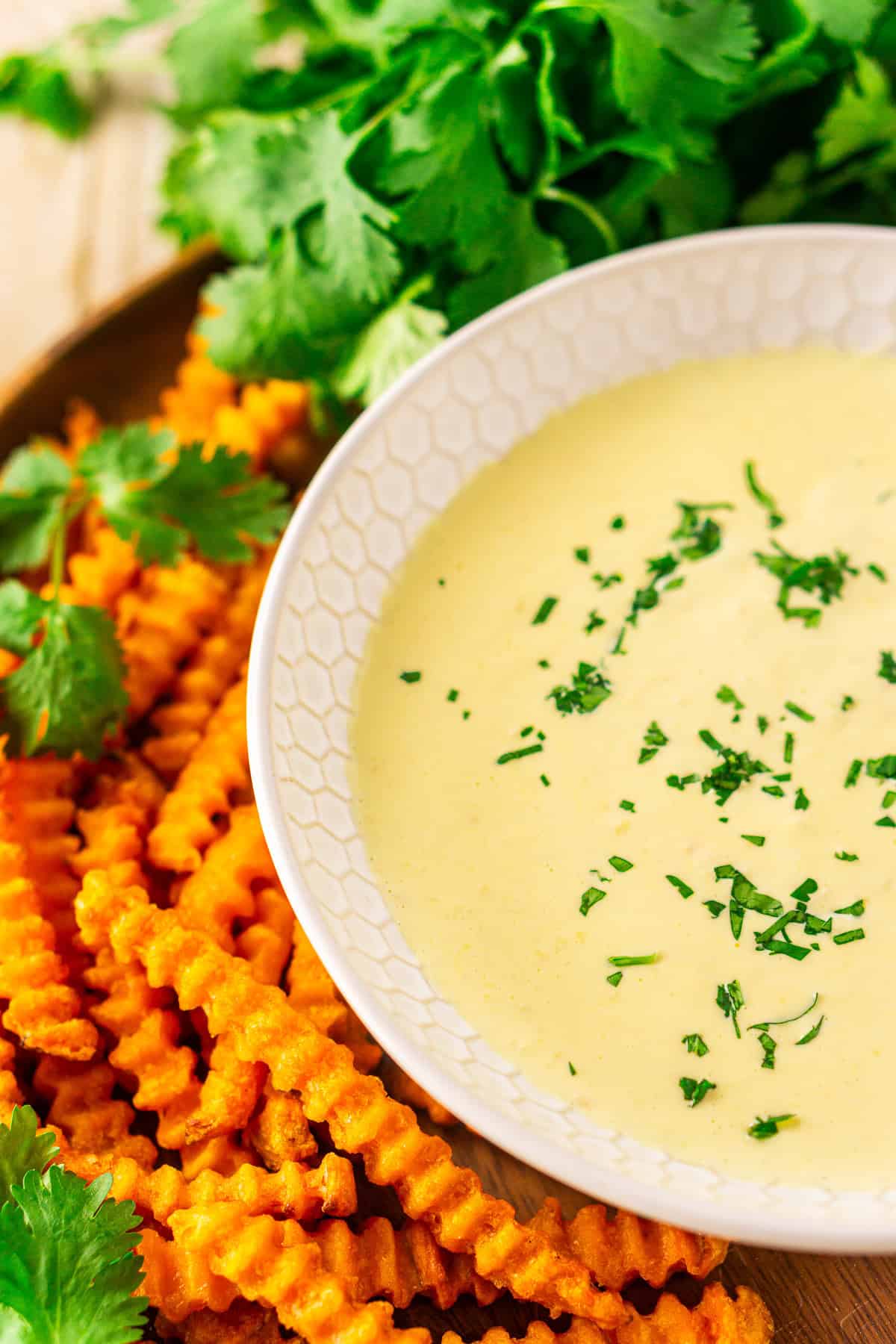 A bowl of mango-habanero aioli sitting on a wooden platter with a serving of sweet potato fries on the side.