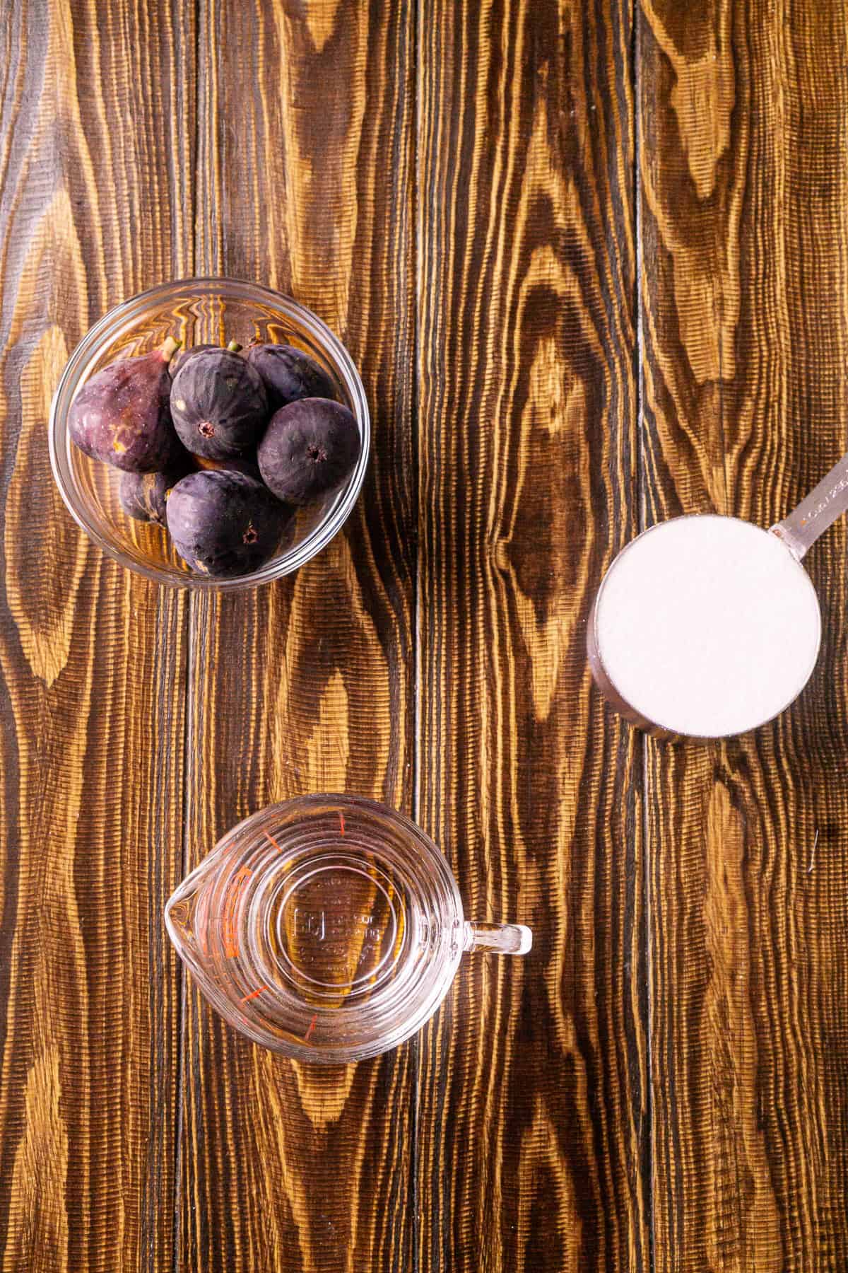 The three fig simple syrup ingredients laid out on a brown wooden surface.
