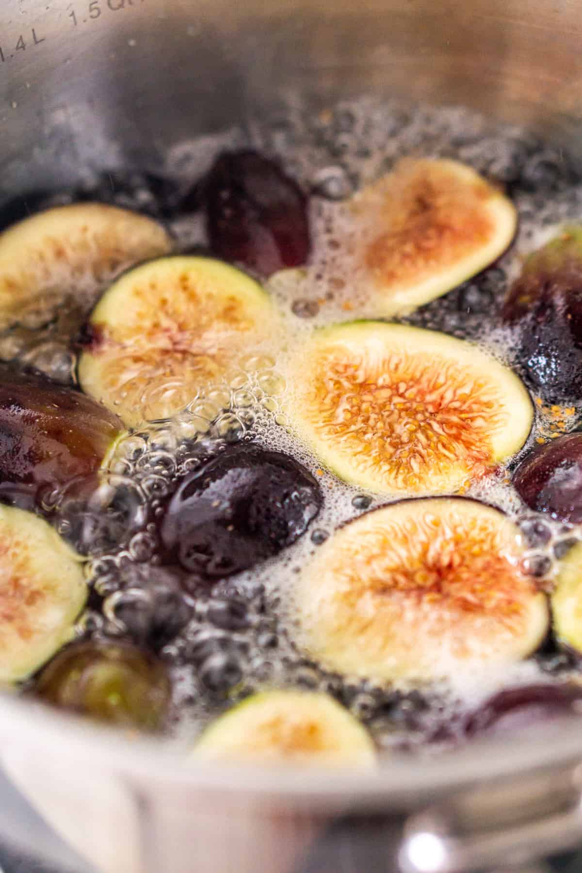 The figs boiling in a small stainless-steel saucepan with the water and white sugar.