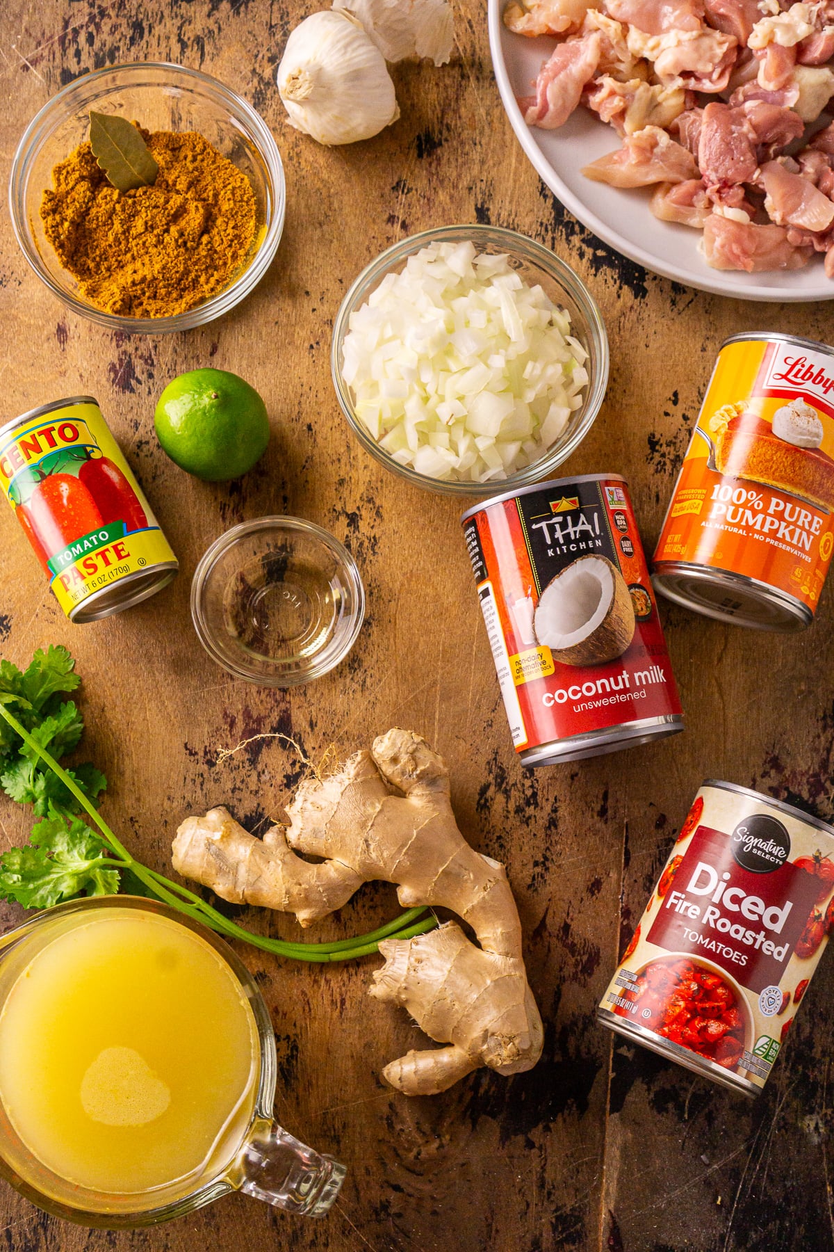 The ingredients for the pumpkin and chicken curry on a dark wooden board.