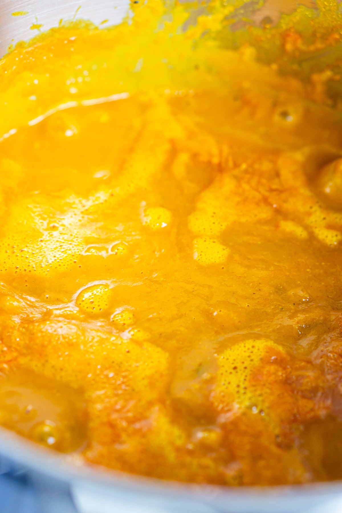 The pumpkin and chicken curry simmering in a stainless-steel pot on the stove.
